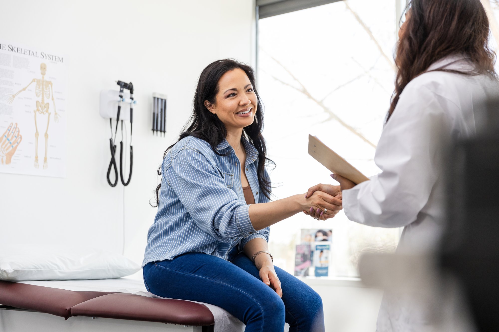 Mid adult female patient shakes hands with her doctor Mid adult female patient shakes hands with her doctor