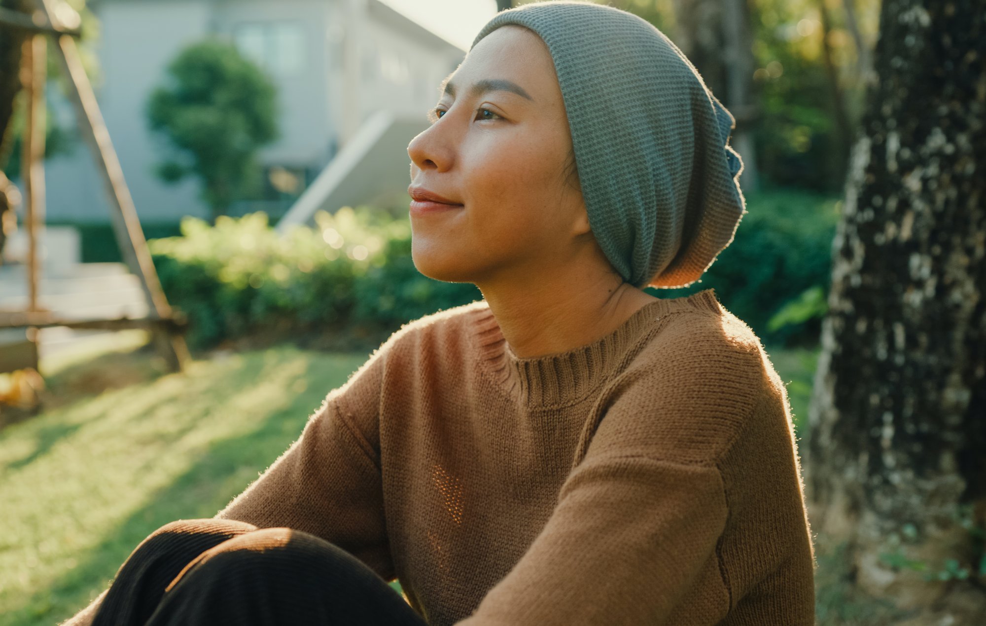 Woman with gray head covering sitting under a tree