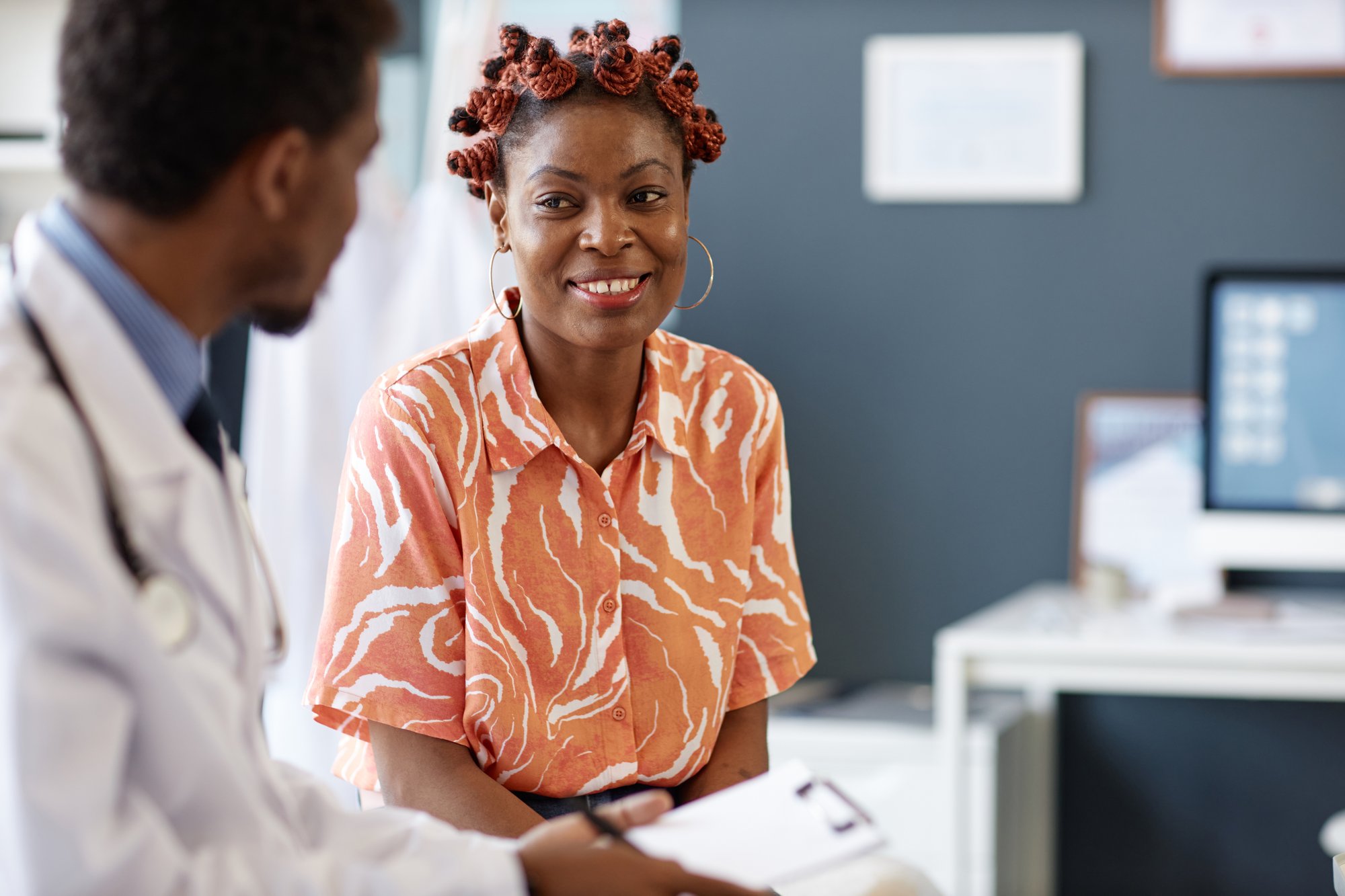 Woman in orange shirt talks with a doctor Woman in orange shirt talks with a doctor